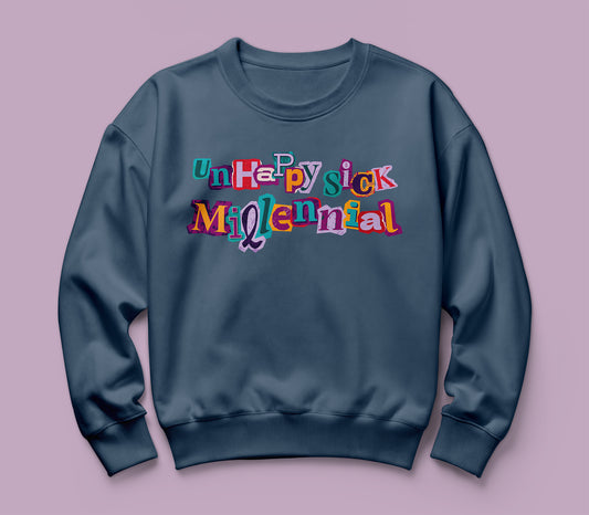A navy blue Comfort Colors crewneck sweatshirt featuring a colorful graphic text print that reads 'unhappy sick millennial' in a playful, multi-colored retro font, displayed against a solid dusty purple background.